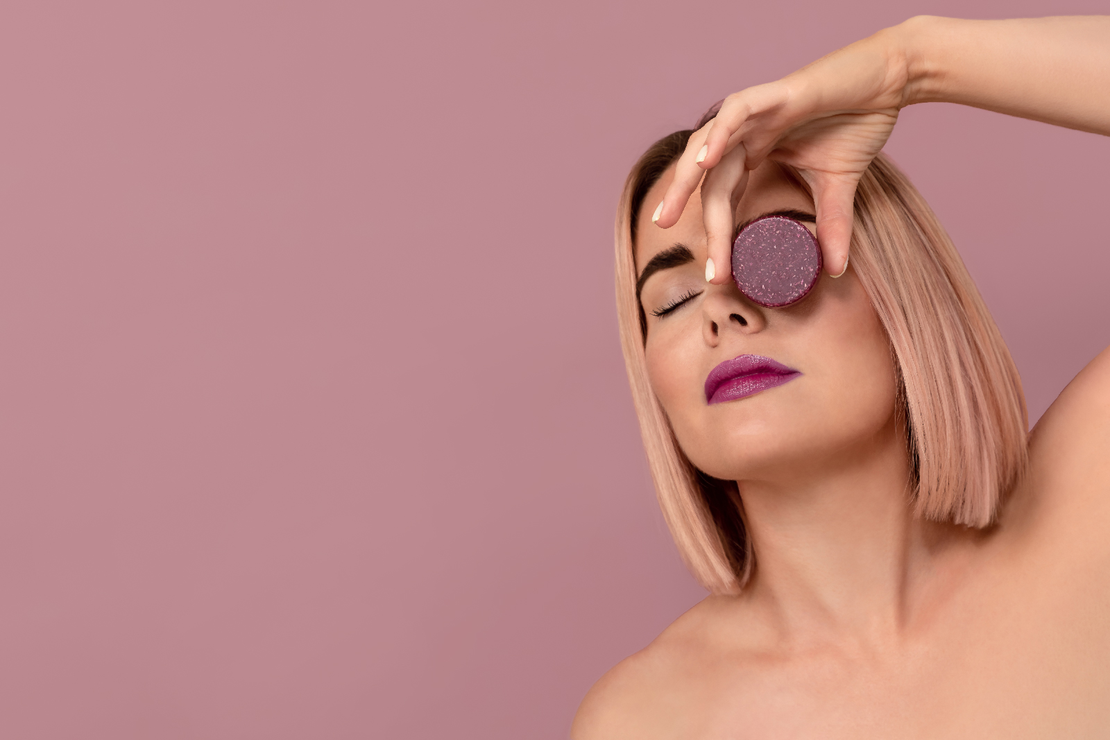 Beauty photoshoot featuring a young woman and a cosmetic container represented on a purple background.